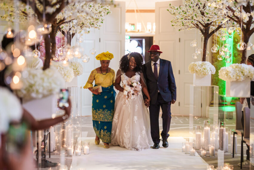 Bride walking down the aisle with family during the wedding ceremony.
