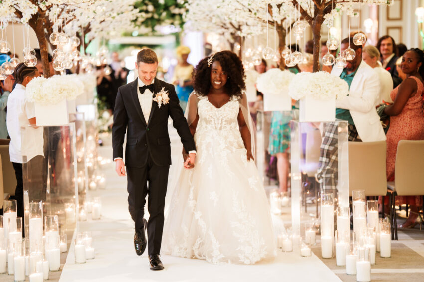 Bride and groom walking hand in hand through the ceremony space.