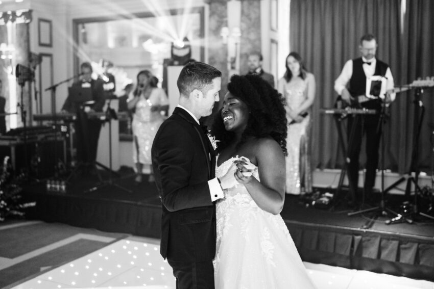 Black and white image of the bride and groom dancing closely together on the dance floor during the evening reception.