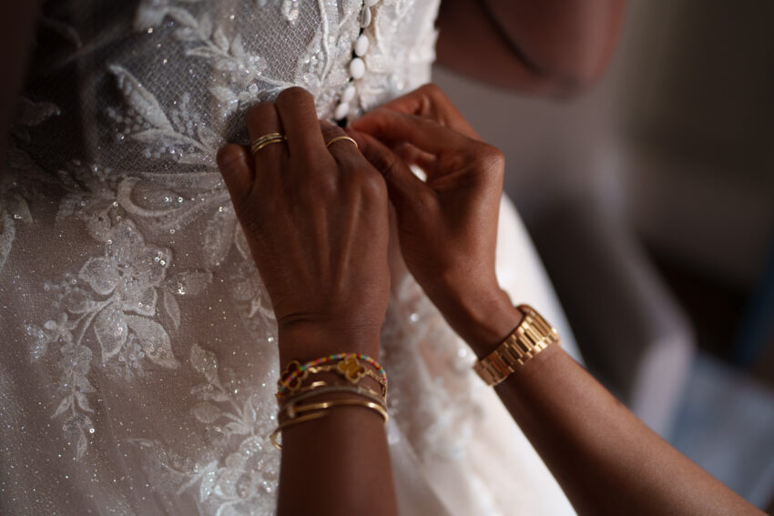 Close-up of bridal jewellery and dress details during wedding preparations.