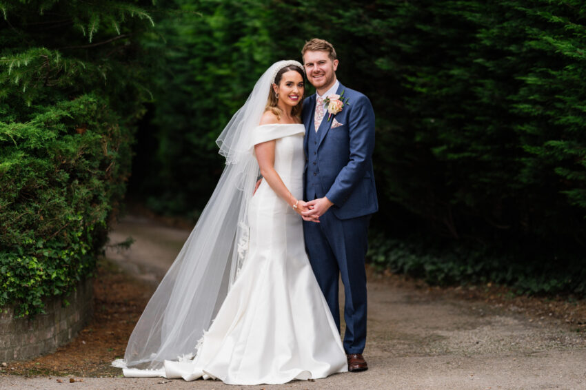 Bride and groom standing together for a relaxed portrait outdoors, framed by greenery and soft natural light after their wedding at Kings Chapel in Amersham.