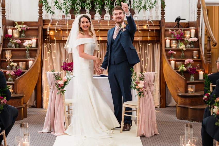 Bride and groom smiling as they are pronounced married, celebrating at the front of Kings Chapel in Amersham.