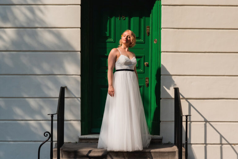 Bride portrait on steps by a green door, relaxed and natural wedding photography