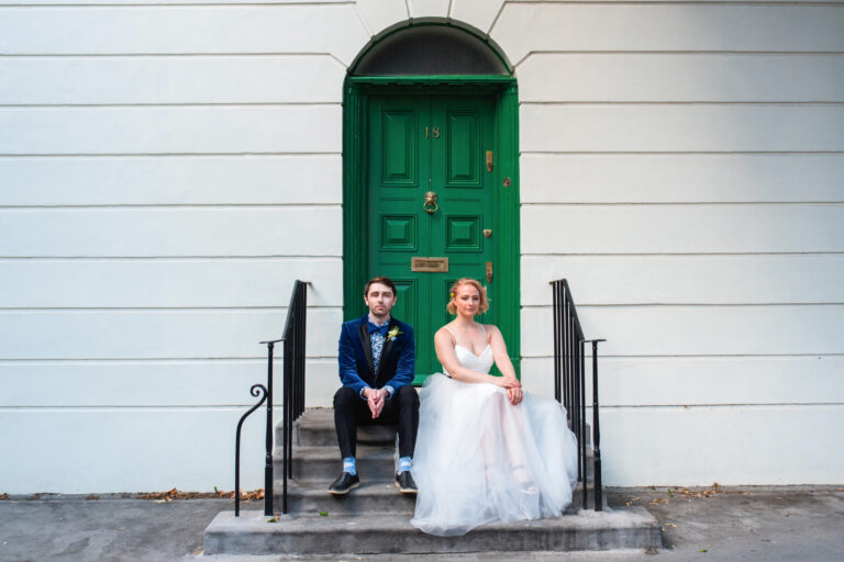 Bride and groom sitting on steps outside a green front door in Islington, relaxed couple photoshoot