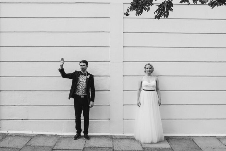 Black and white couple portrait against a white wall in London, playful wedding photoshoot