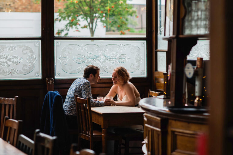 Bride and groom having a drink together in a cosy London pub, candid couple moment