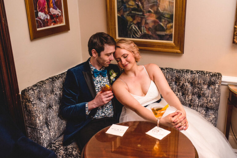 Bride and groom relaxing with drinks in an elegant London bar, intimate couple portrait