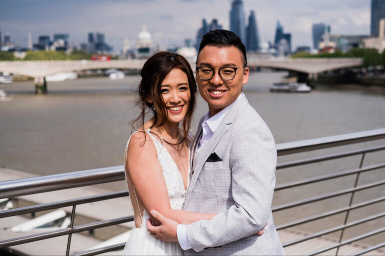 Couple portrait on a riverside walkway in London with city skyline in the background