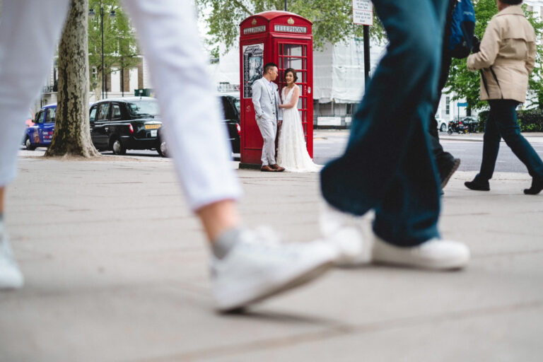 Couple portrait by a classic red telephone box in London, candid street moment