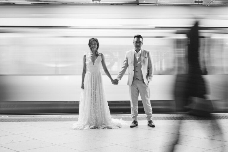 Black and white couple portrait at Westminster Station in London with the Tube rushing past