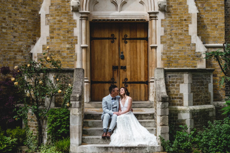 Bride and groom sitting on church steps outside a historic London church, relaxed couple portrait