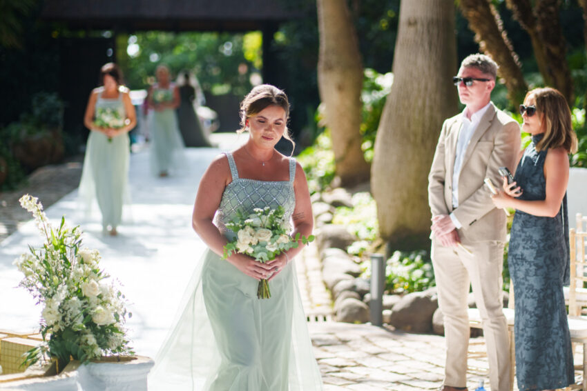 Bridesmaid walking down the aisle holding a bouquet during ceremony at Marbella Club Hotel.