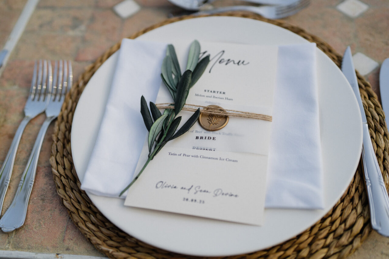 Wedding table setting at a Malaga venue with menu, olive branch and elegant details.