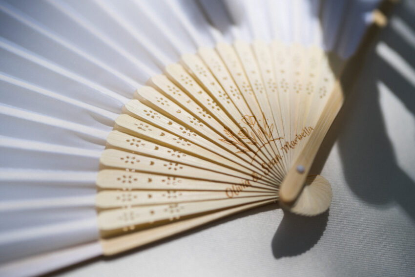 Close-up detail of elegant hand fan on white fabric.