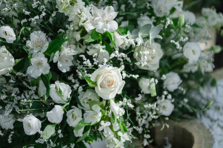 White wedding flowers arranged with greenery in soft natural light.