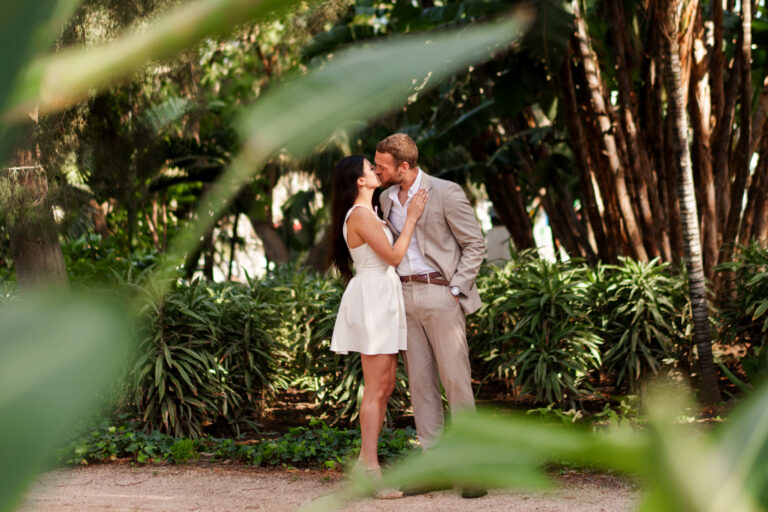 Couple kissing among palm trees during a romantic couples photoshoot in Málaga.