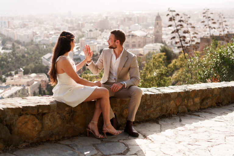 Couple laughing together on the Gibralfaro viewpoint overlooking the city of Málaga.
