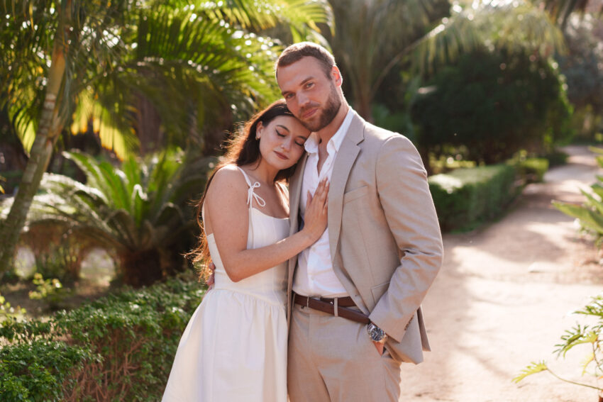 Couple embracing on a palm-lined garden path during a relaxed Málaga couples photoshoot.
