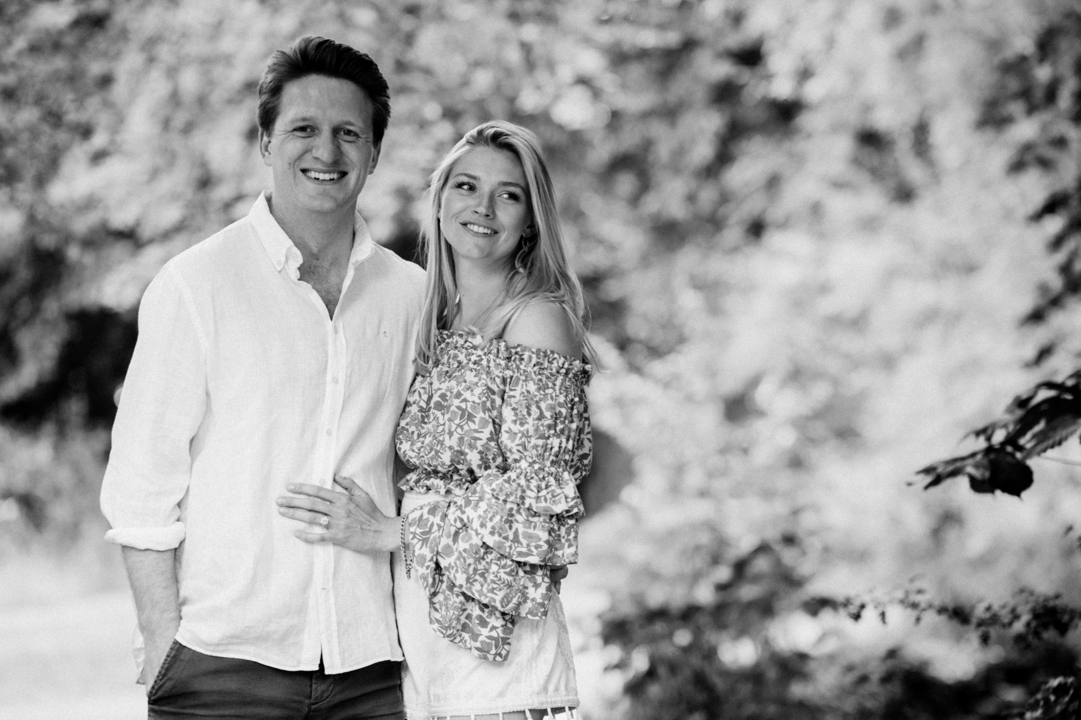 Couple standing together in soft dappled light in Cambridge, black and white portrait with natural, relaxed feel.