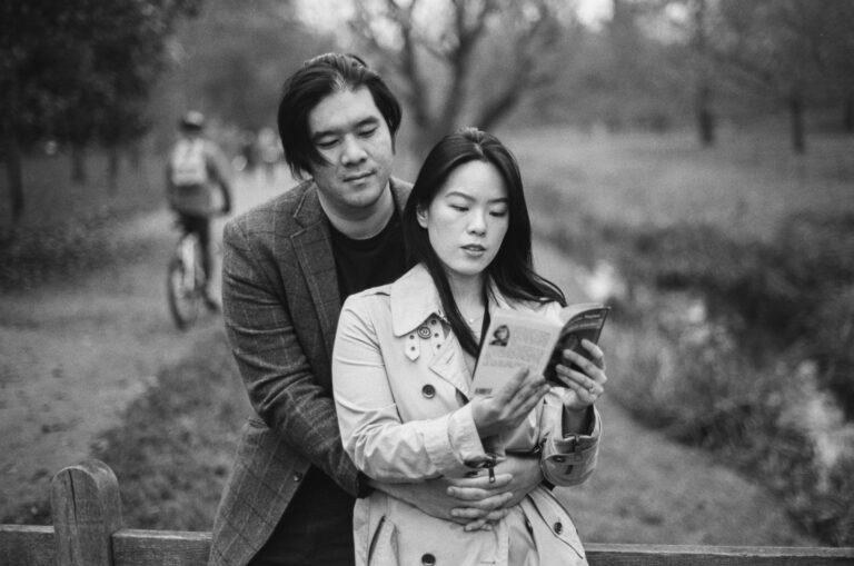 Couple standing together reading a book along The Backs in Cambridge.