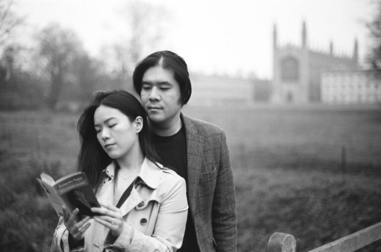 Intimate portrait of a couple reading together on The Backs in Cambridge.