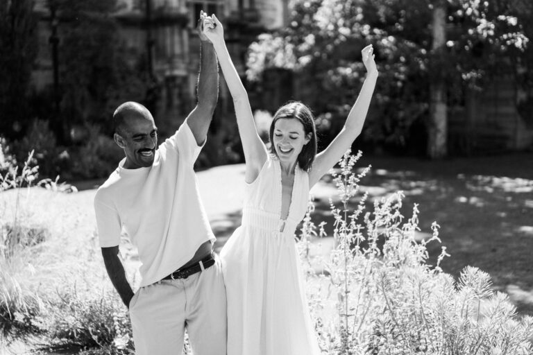 Joyful couple celebrating together in a Cambridge college garden.