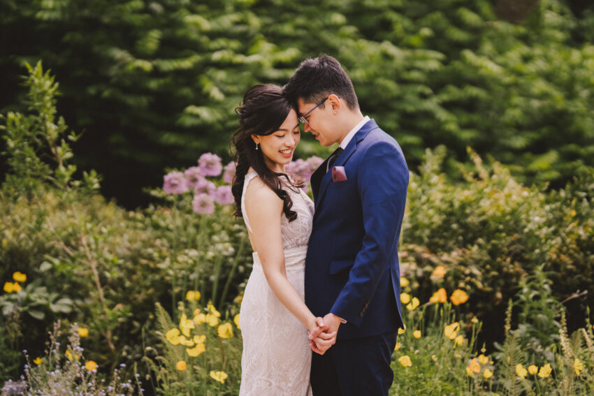An elegantly dressed couple pictured amongst the flowers of Cambridge Botanic Garden