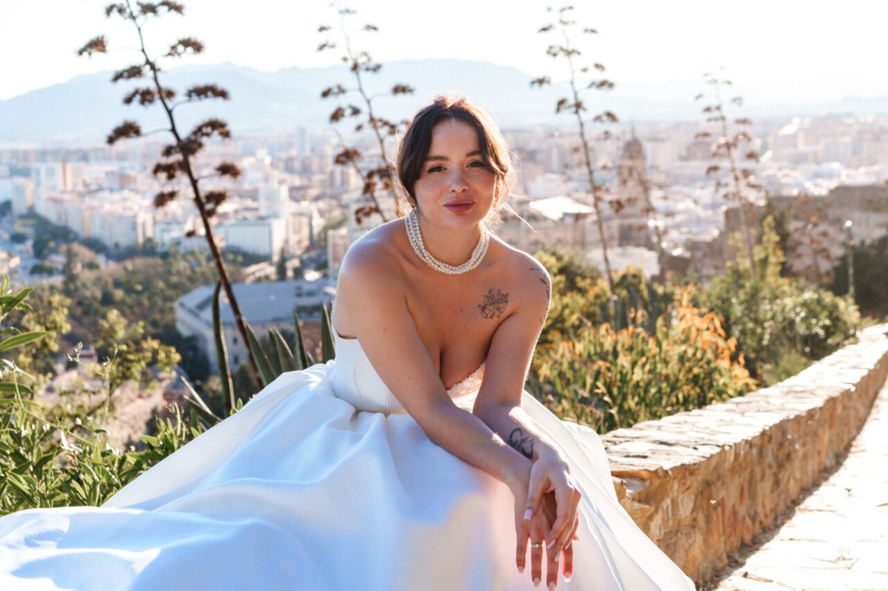 Close-up bridal portrait at Gibralfaro hill with Malaga skyline in the background.