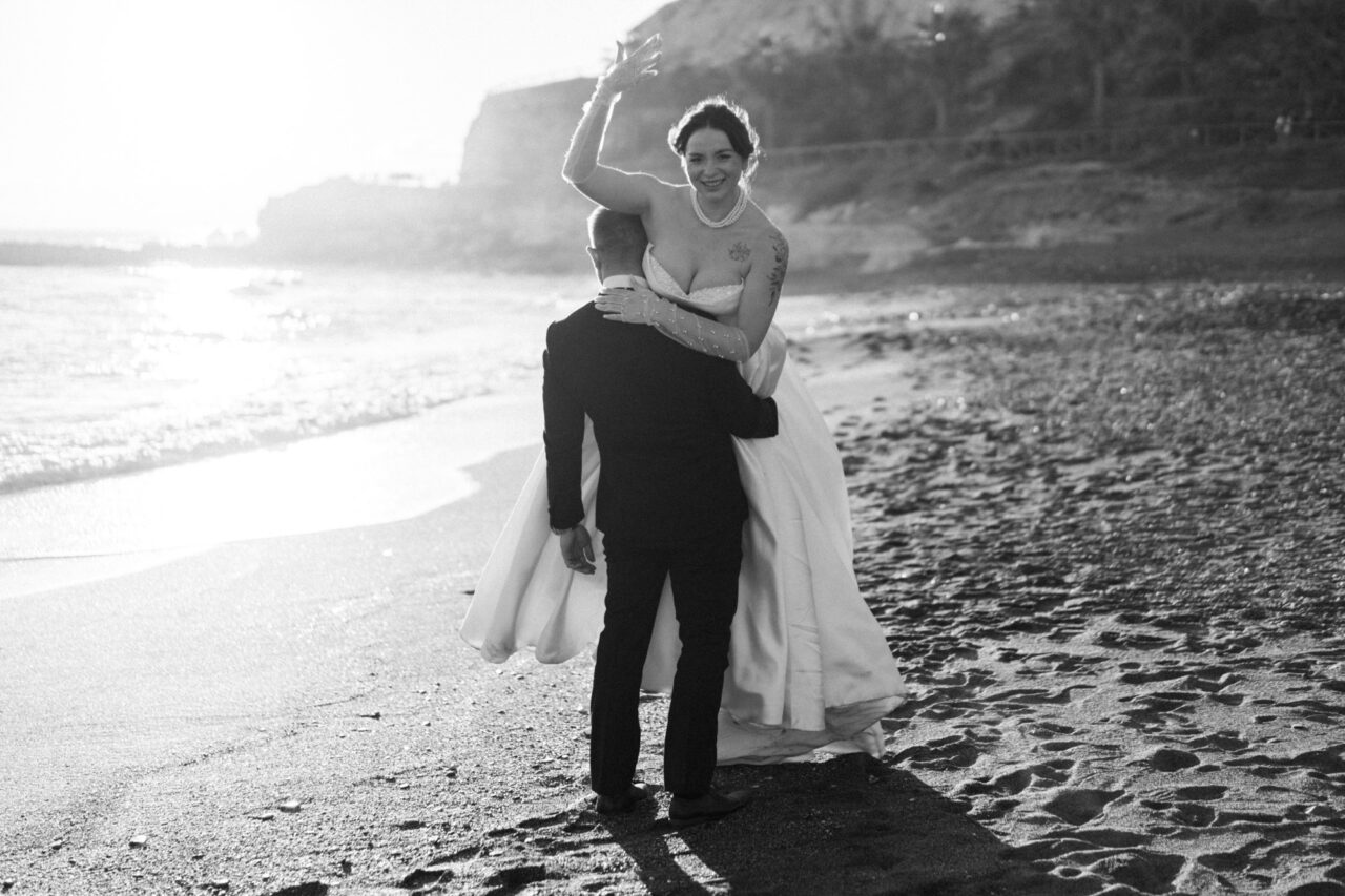 Bride and groom on Malaga beach at sunset, black and white wedding photograph.