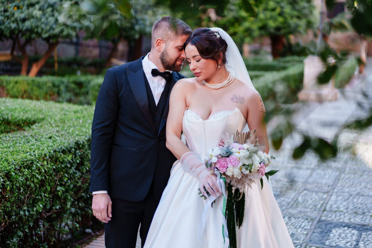 Close portrait of bride and groom in Malaga gardens, soft light and greenery.