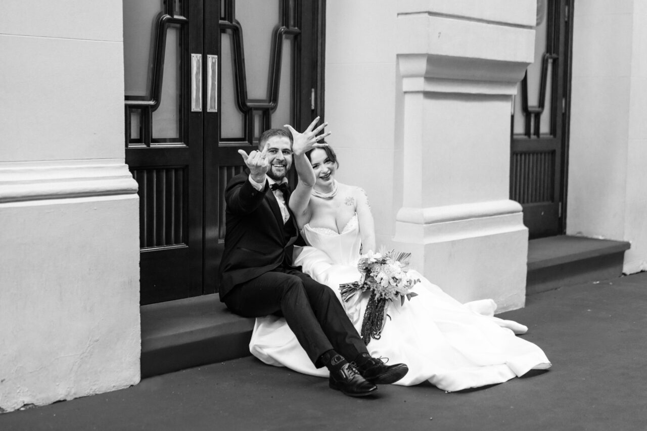 Bride and groom sitting outside theatre doors in Malaga, relaxed candid moment.