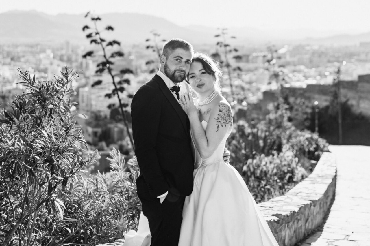 Bride and groom portrait at Gibralfaro hill overlooking Malaga, soft black and white tones.