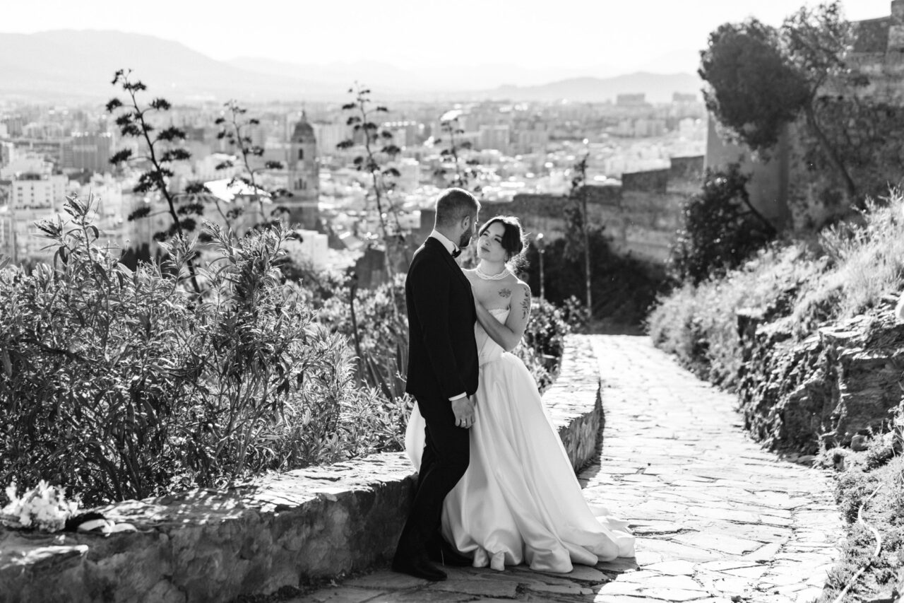 Bride and groom overlooking Malaga from Gibralfaro hill, black and white portrait by a Malaga wedding photographer.