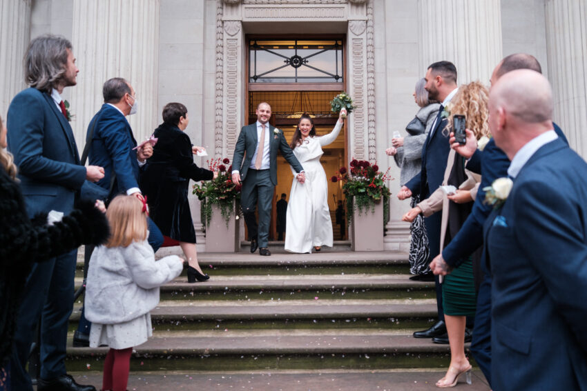 Bride and groom celebrating on the steps of Old Marylebone Town Hall after their ceremony.