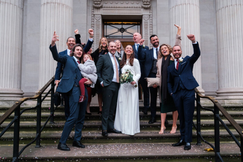Friends cheering and celebrating with the couple outside Old Marylebone Town Hall.