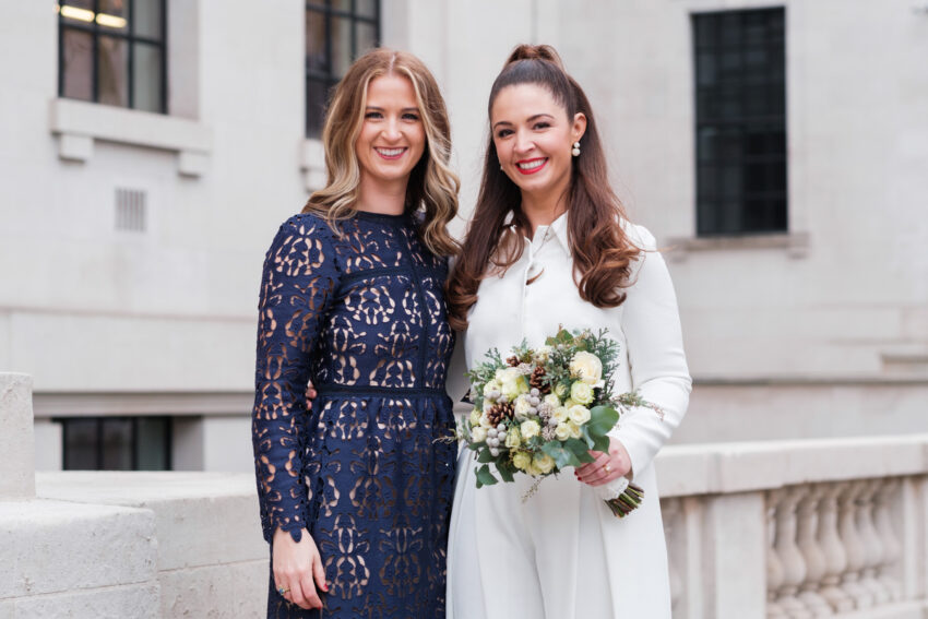 Bride smiling with a bridesmaid outside Old Marylebone Town Hall.
