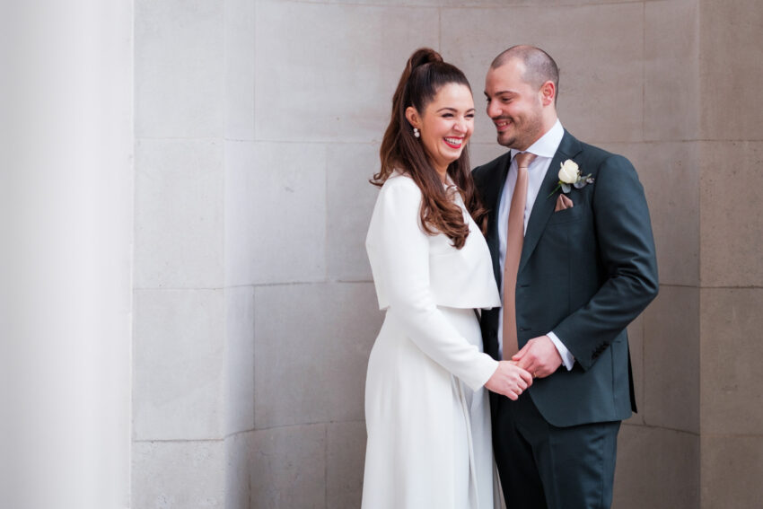 Bride and groom smiling together outside Old Marylebone Town Hall after their ceremony.