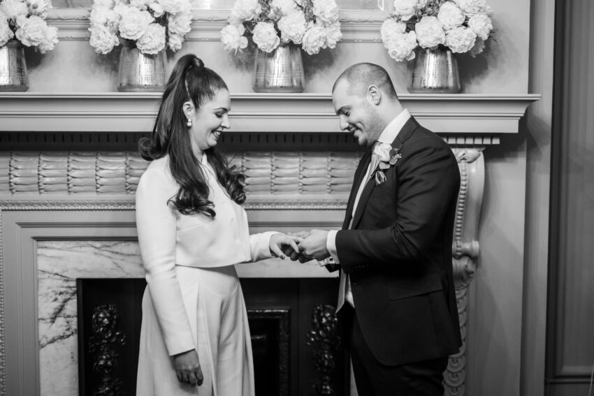 Groom placing a wedding ring on the bride’s finger in the Pimlico Room at Old Marylebone Town Hall.