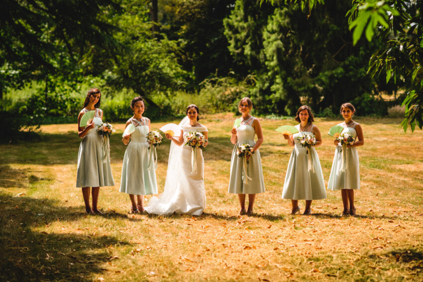 Bride and bridesmaids standing together in the gardens at Swynford Manor wedding venue Cambridgeshire.