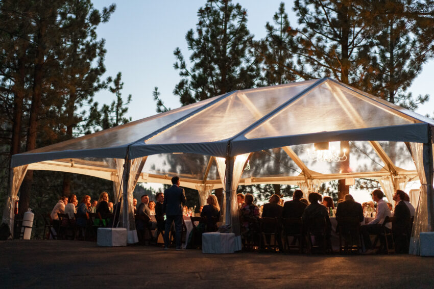 Evening wedding reception under a clear marquee surrounded by pine trees at Tahoe Mountain Home.