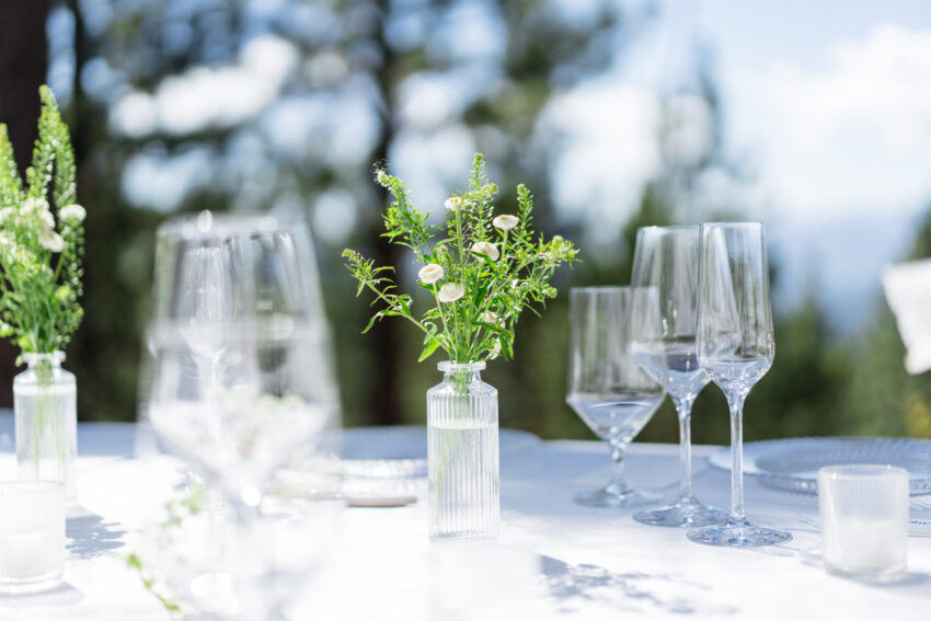 Wedding table details with flowers and glassware overlooking Lake Tahoe.