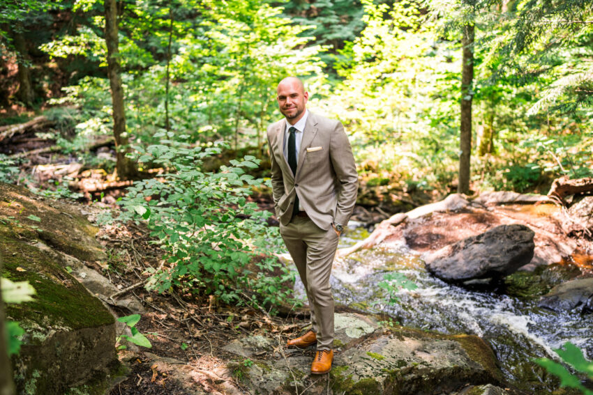 Groom portrait beside a woodland stream at Trillium Resort & Spa in Muskoka.