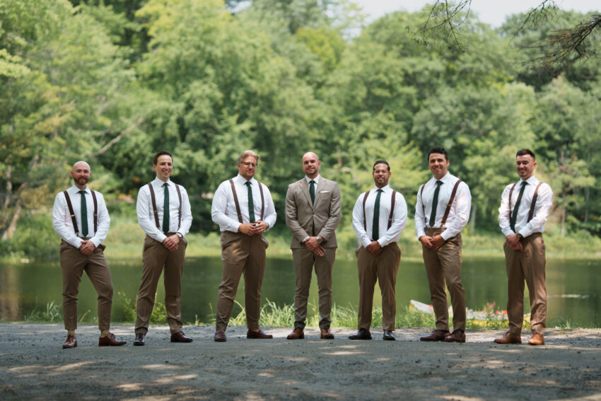 Groom and groomsmen lined up beside the lake during a Trillium Resort & Spa wedding.