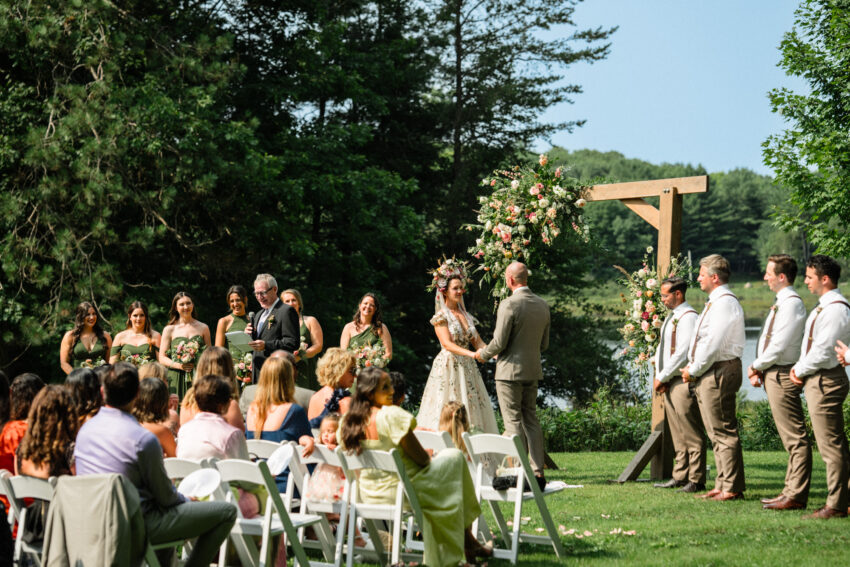 Bride and groom standing beneath the floral ceremony arch during their wedding at Trillium Resort & Spa.