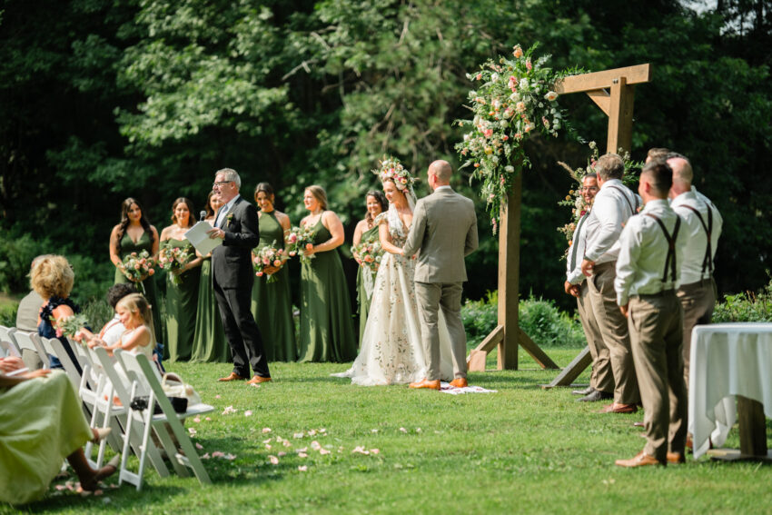 Wedding ceremony with bride, groom and bridal party beneath a floral arch at Trillium Resort & Spa.