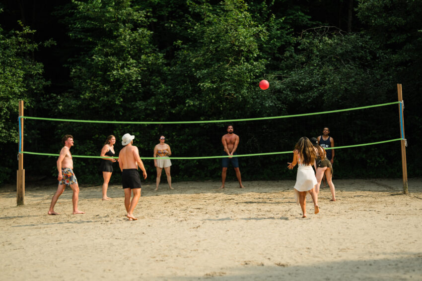 Friends playing volleyball beside the forest during a summer wedding weekend at Trillium Resort & Spa.