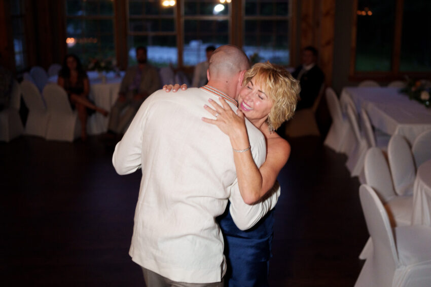Guest hugging the groom on the dance floor during the reception at Trillium Resort & Spa.