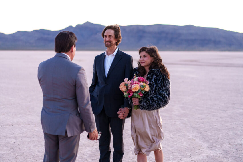Couple holding hands during an intimate desert ceremony with officiant at sunset, captured by a Las Vegas elopement photographer on the dry lake bed.