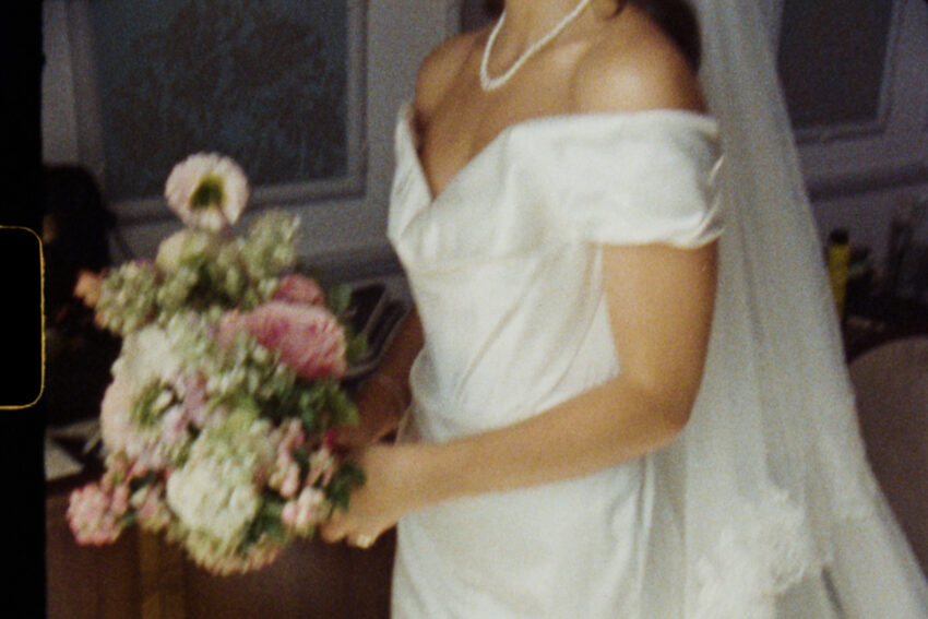 Bride holding a bouquet in a softly lit room, captured on film with a nostalgic feel, reflecting the atmosphere of a Las Vegas elopement.