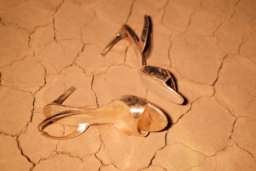Bride’s gold high heels resting on cracked desert ground in warm light, captured as a detail shot by a Las Vegas elopement photographer.